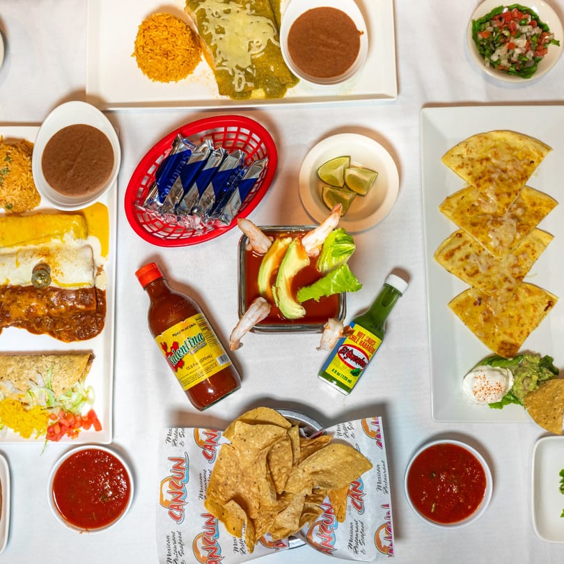 Overhead view of a table laden with various Mexican dishes, including enchiladas, quesadillas, and tacos.