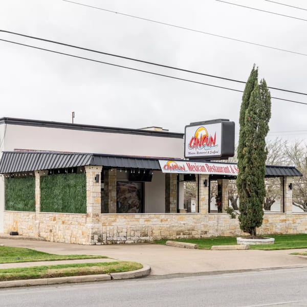 Exterior of Cancun Mexican Restaurant, a stone building with a black awning and prominent signage.