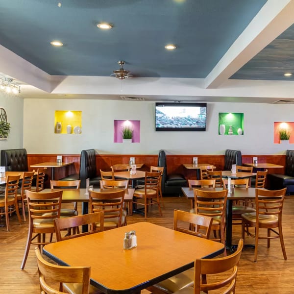 Spacious dining room at Cancun Mexican Restaurant with wooden tables, chairs, and dark booths.