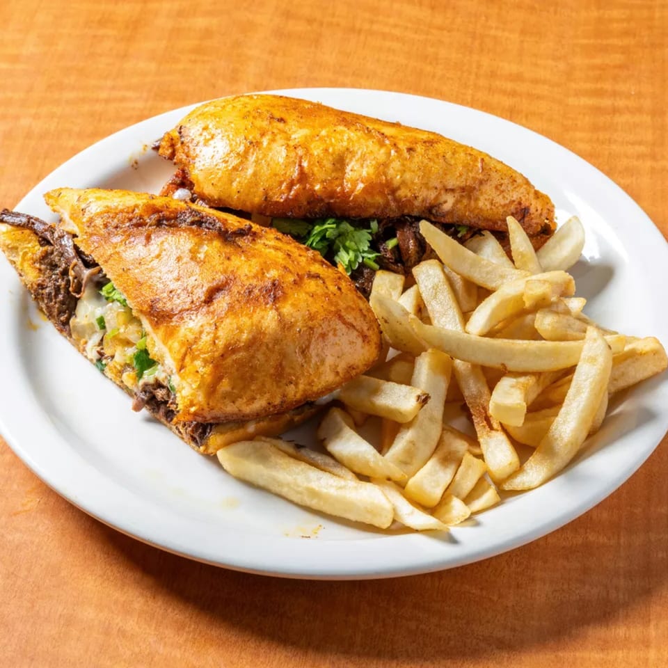 Two golden-brown Mexican tortas filled with meat and cheese, served with a side of french fries.